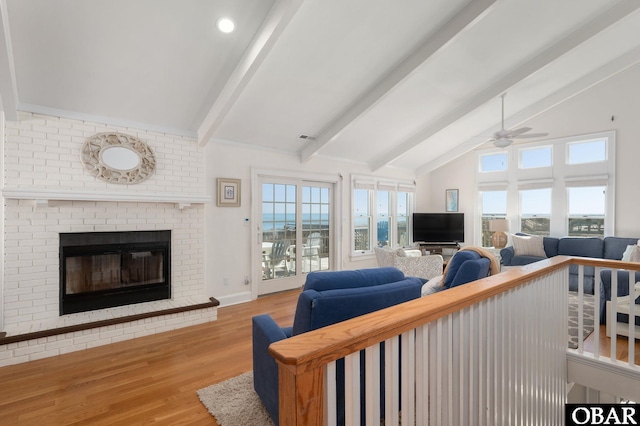 living room featuring visible vents, lofted ceiling with beams, wood finished floors, a fireplace, and ceiling fan