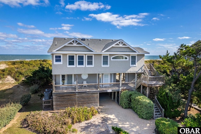 view of front of house featuring a water view, dirt driveway, covered porch, a carport, and stairs