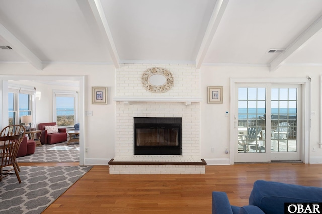 living room with beam ceiling, wood finished floors, and a wealth of natural light