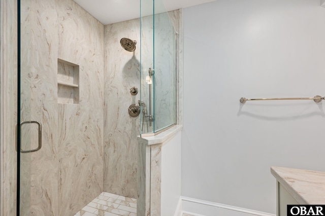 bathroom with a marble finish shower and baseboards