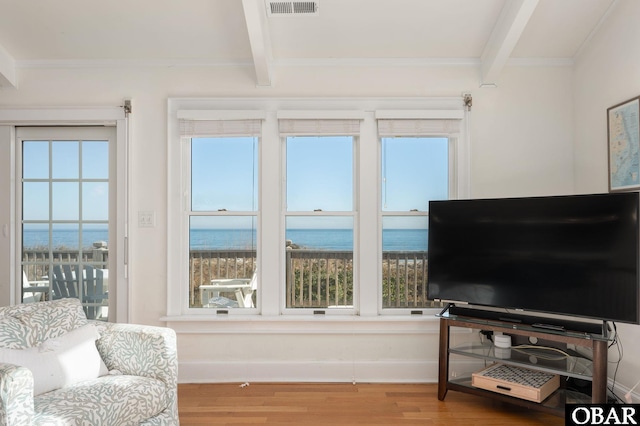 living area featuring beam ceiling, wood finished floors, visible vents, and ornamental molding