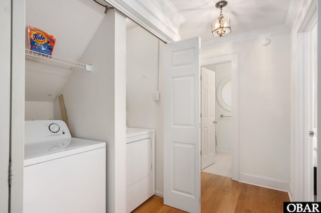 washroom featuring light wood-style flooring, ornamental molding, washing machine and dryer, baseboards, and laundry area