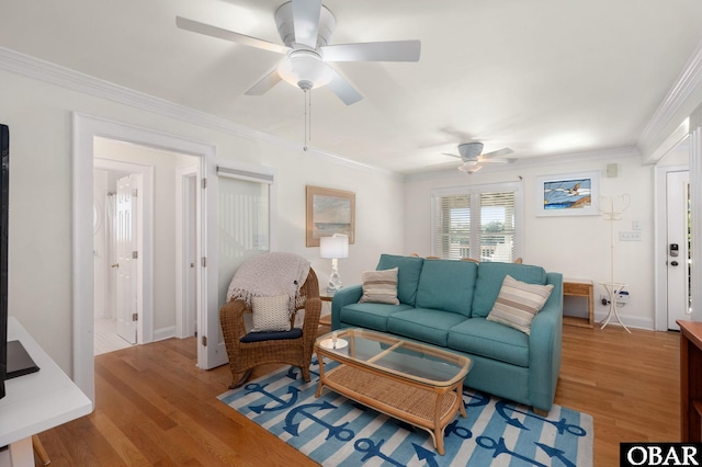 living area with wood finished floors, a ceiling fan, baseboards, and ornamental molding