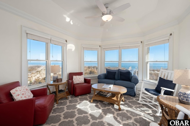 living room featuring ceiling fan, a water view, a raised ceiling, and ornamental molding