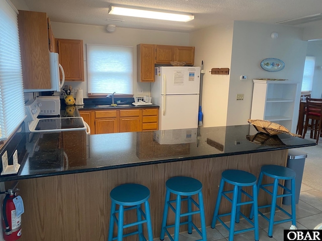 58221 Liberator Way Lot 1-3, Hatteras, NC 27943 - kitchen featuring white appliances, a peninsula, a kitchen breakfast bar, and brown cabinetry