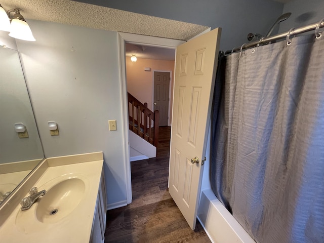 full bathroom with baseboards, shower / tub combo with curtain, vanity, wood finished floors, and a textured ceiling