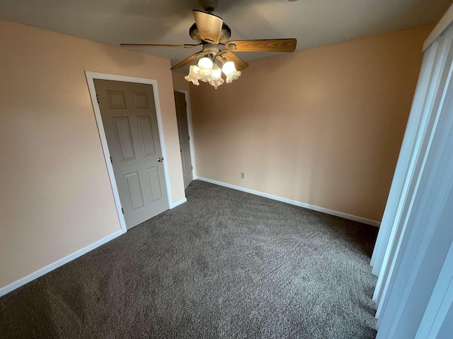 unfurnished bedroom with baseboards, a ceiling fan, and dark carpet