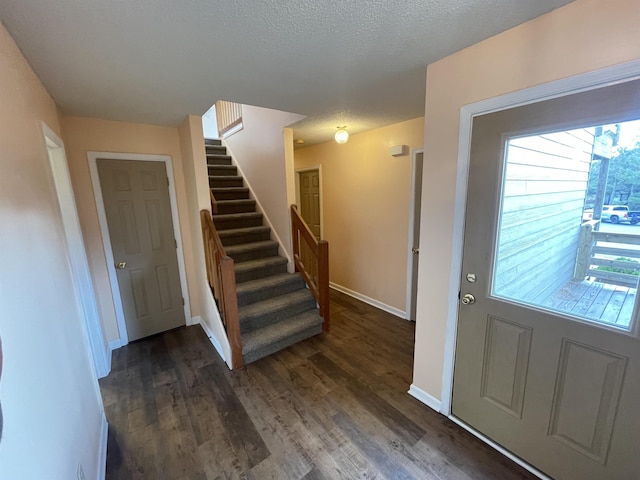 foyer with dark wood finished floors, a textured ceiling, stairs, and baseboards