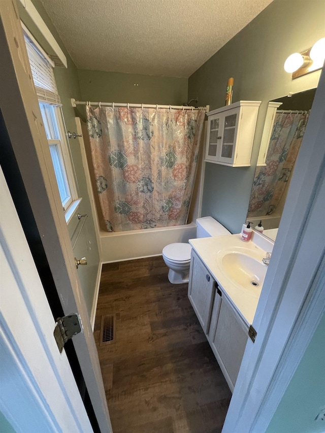 full bath featuring visible vents, shower / tub combo, wood finished floors, a textured ceiling, and vanity