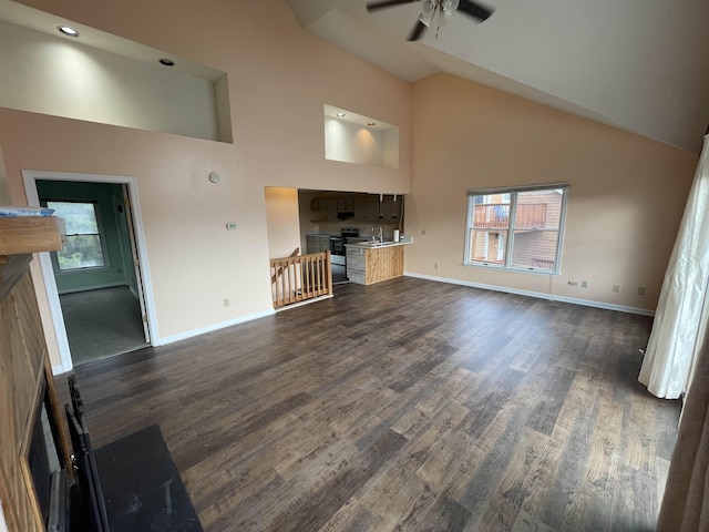 unfurnished living room with baseboards, dark wood-style flooring, and high vaulted ceiling