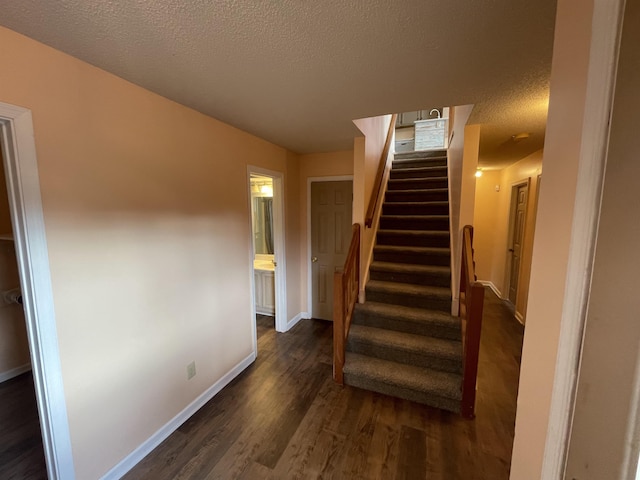 stairway with baseboards, a textured ceiling, and wood finished floors