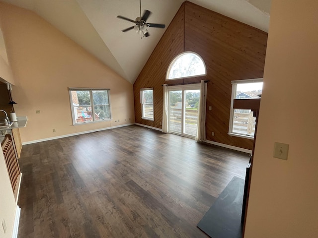 unfurnished living room featuring a ceiling fan, baseboards, dark wood-type flooring, and high vaulted ceiling