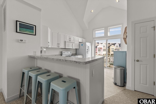 1107 Cambridge Rd Unit 305-F, Kill Devil Hills, NC 27948 - kitchen featuring white appliances, high vaulted ceiling, a peninsula, a breakfast bar area, and white cabinetry