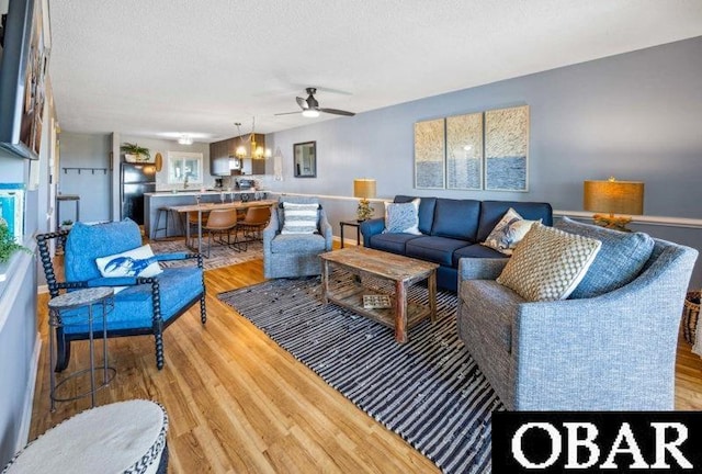 24250 Resort Rodanthe Dr Unit 12B, Rodanthe, NC 27968 - living area featuring a ceiling fan, light wood finished floors, a chandelier, and a textured ceiling