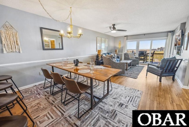 24250 Resort Rodanthe Dr Unit 12B, Rodanthe, NC 27968 - dining area featuring a ceiling fan, a textured ceiling, a chandelier, and wood finished floors
