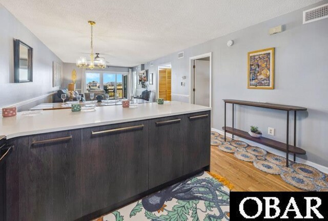24250 Resort Rodanthe Dr Unit 12B, Rodanthe, NC 27968 - kitchen with light wood-type flooring, open floor plan, light countertops, a chandelier, and a peninsula