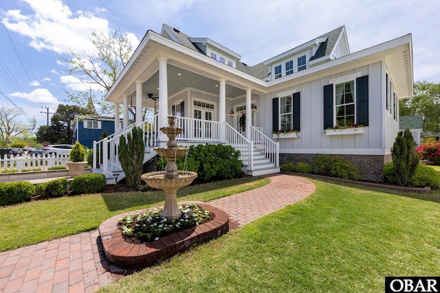 504 Lord Essex Ave, Manteo, NC 27954 - view of front of property with a front lawn, roof with shingles, a ceiling fan, board and batten siding, and a porch