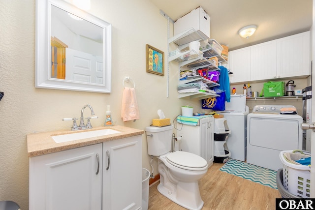 half bath featuring washer and dryer, vanity, toilet, and wood finished floors