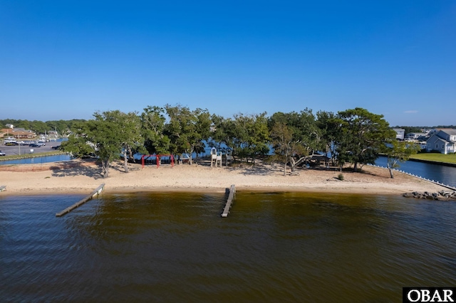 view of dock featuring a water view and a beach view