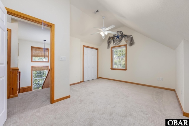 unfurnished bedroom featuring carpet flooring, lofted ceiling, multiple windows, and visible vents