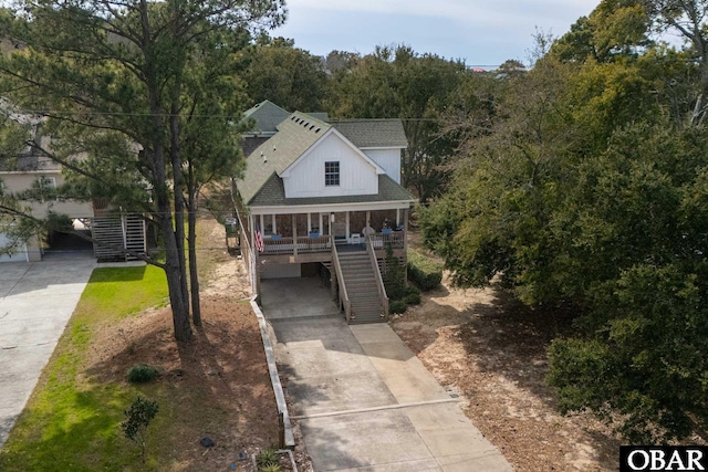 view of front facade with stairway, a porch, concrete driveway, and roof with shingles