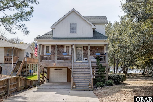 coastal inspired home featuring a porch, stairway, an attached garage, and driveway