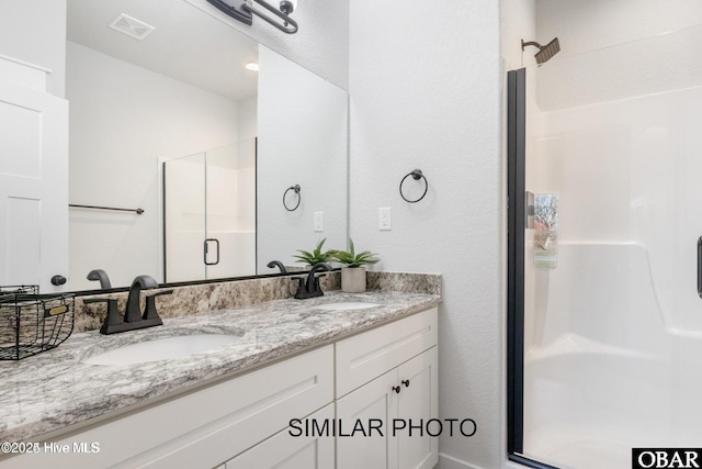 bathroom with a stall shower, visible vents, a sink, and double vanity