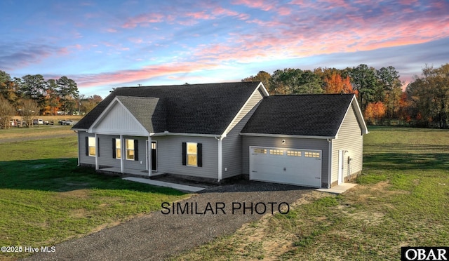 view of front of home featuring a garage, roof with shingles, a yard, and driveway