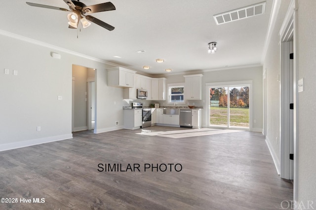 unfurnished living room featuring baseboards, visible vents, a ceiling fan, ornamental molding, and wood finished floors