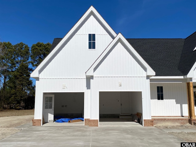 exterior space featuring concrete driveway and roof with shingles