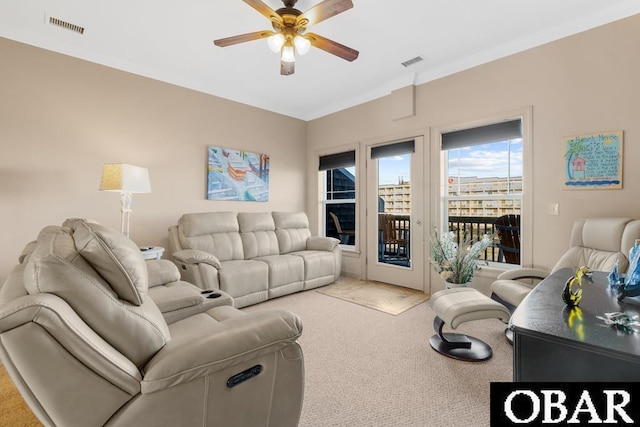 living area featuring ceiling fan, visible vents, and light colored carpet