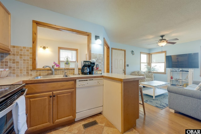2009 Wrightsville Blvd Unit 4-B, Kill Devil Hills, NC 27948 - kitchen featuring white dishwasher, a sink, healthy amount of natural light, decorative backsplash, and a textured ceiling