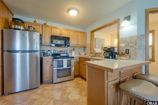 2009 Wrightsville Blvd Unit 4-B, Kill Devil Hills, NC 27948 - kitchen with stainless steel appliances, a peninsula, tile countertops, a sink, and a kitchen breakfast bar