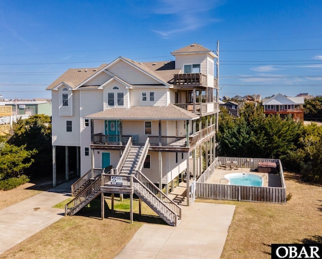 rear view of property featuring a lawn, a fenced in pool, a balcony, a residential view, and stairs