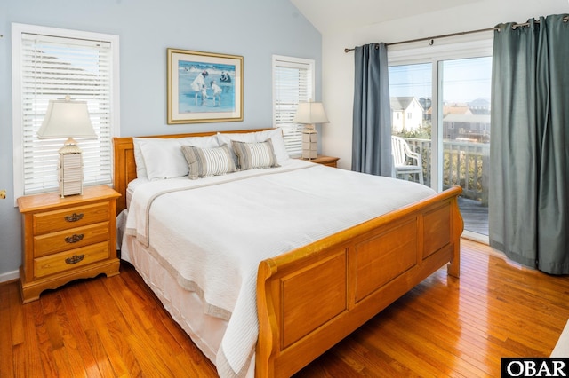 bedroom with access to outside, vaulted ceiling, and wood finished floors