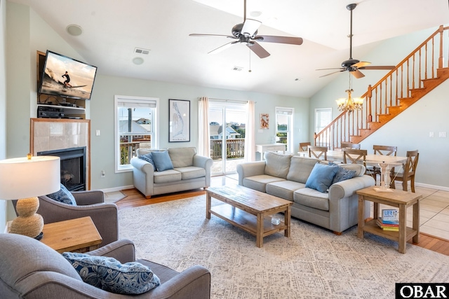 living room featuring vaulted ceiling, a fireplace, stairway, and baseboards