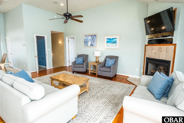 living room featuring baseboards, a tile fireplace, wood finished floors, high vaulted ceiling, and recessed lighting