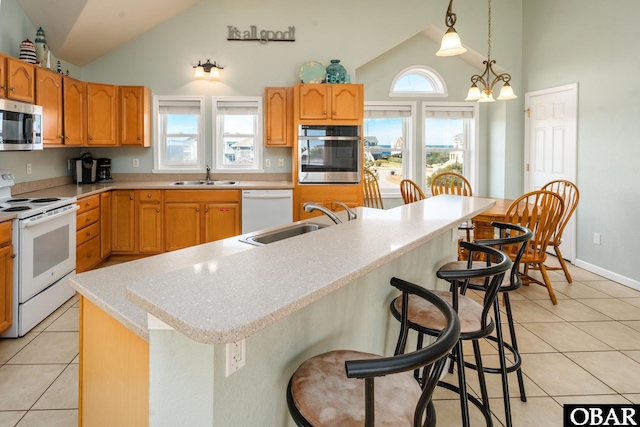 kitchen with appliances with stainless steel finishes, light countertops, hanging light fixtures, and a center island with sink