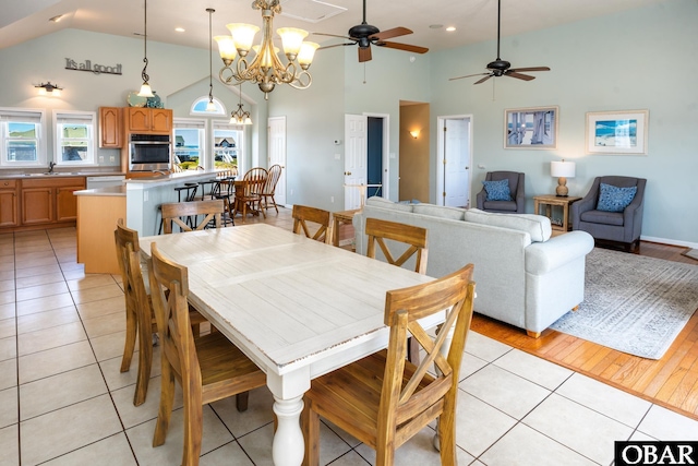 dining area featuring high vaulted ceiling, light tile patterned flooring, and an inviting chandelier