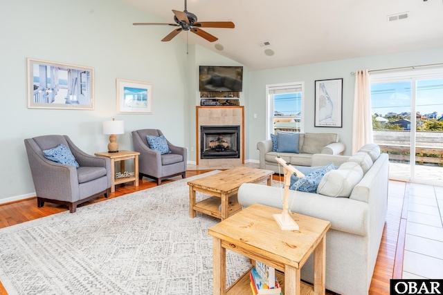 living area with plenty of natural light, visible vents, vaulted ceiling, and wood finished floors