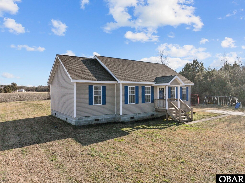 view of front facade with crawl space, a shingled roof, and a front lawn