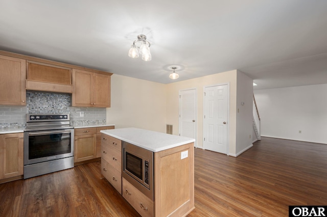 3002 Seahorse Ct Unit 3002, Kitty Hawk, NC 27949 - kitchen featuring appliances with stainless steel finishes, tasteful backsplash, light countertops, dark wood-style floors, and a center island
