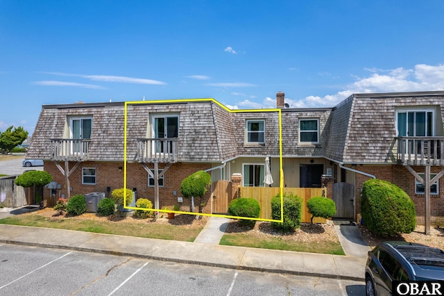 3002 Seahorse Ct Unit 3002, Kitty Hawk, NC 27949 - view of front facade with mansard roof, a gate, brick siding, and a chimney