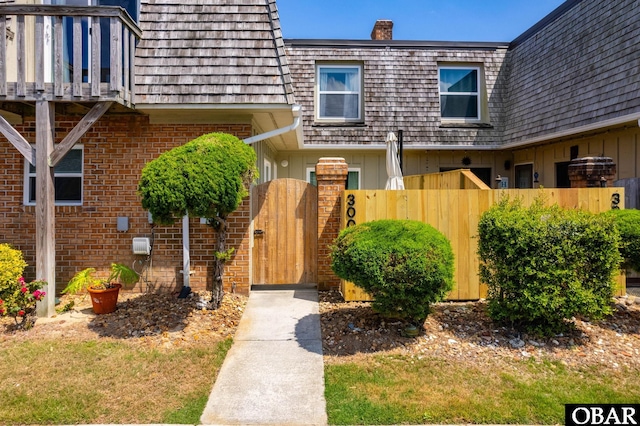 3002 Seahorse Ct Unit 3002, Kitty Hawk, NC 27949 - entrance to property featuring fence, mansard roof, a gate, brick siding, and board and batten siding