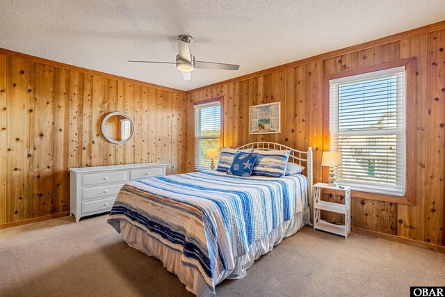 bedroom featuring light carpet, multiple windows, a textured ceiling, and wooden walls