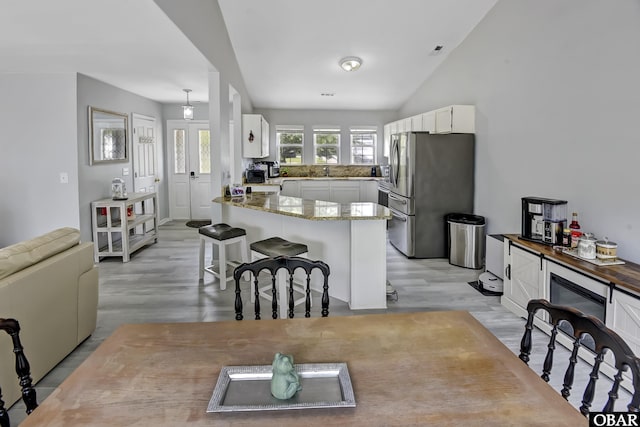 192 Colingwood Ln Lot 22, Kill Devil Hills, NC 27948 - kitchen featuring freestanding refrigerator, a peninsula, white cabinets, a kitchen bar, and light wood finished floors