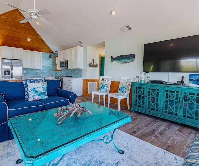 living area with ceiling fan, visible vents, lofted ceiling, and wood finished floors