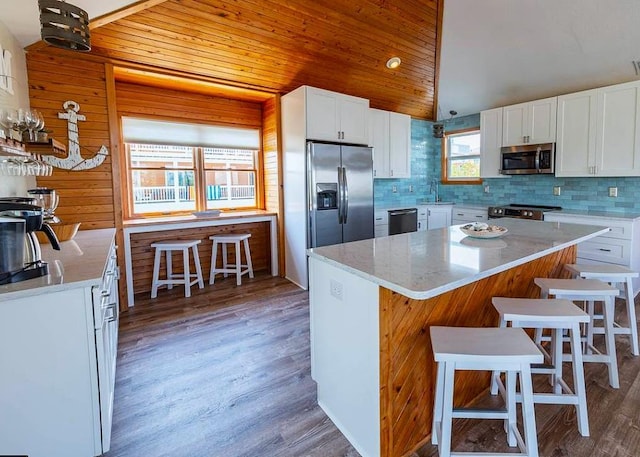 kitchen with a kitchen bar, lofted ceiling, appliances with stainless steel finishes, and decorative backsplash