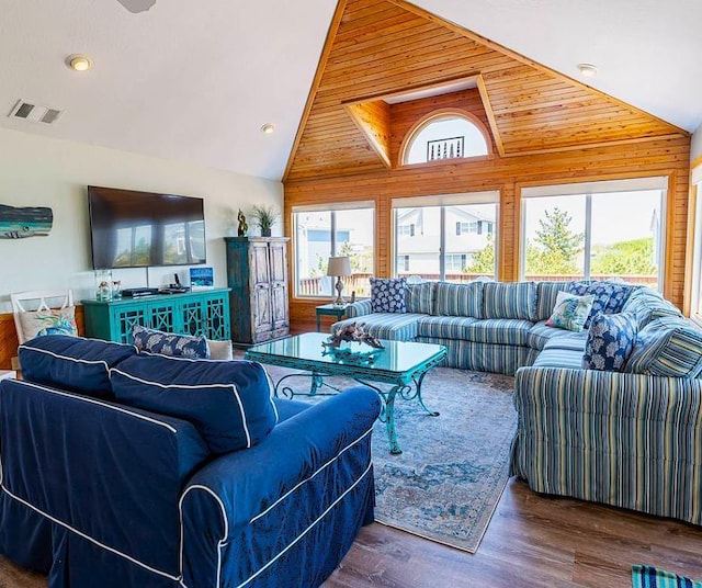 living area with wooden walls, high vaulted ceiling, visible vents, and wood finished floors