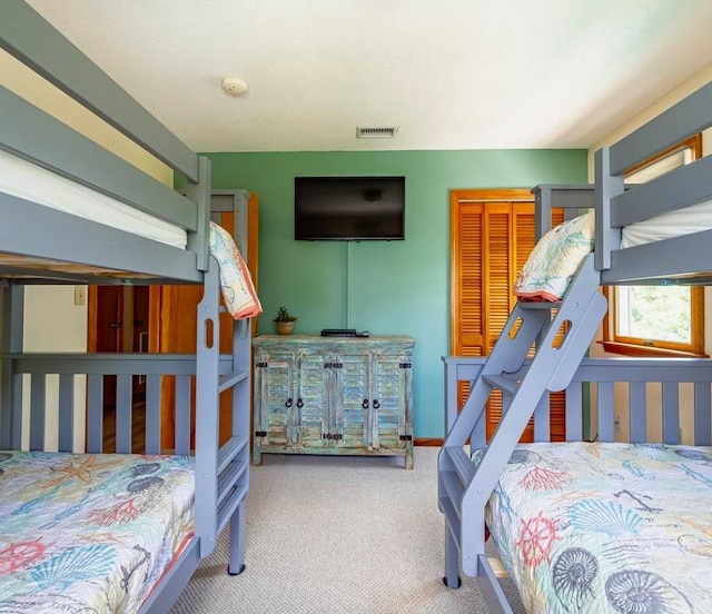 carpeted bedroom with visible vents, baseboards, and a closet